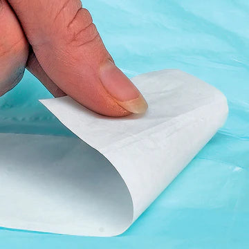 Hand peeling a sheet of paper from a roll on a blue background